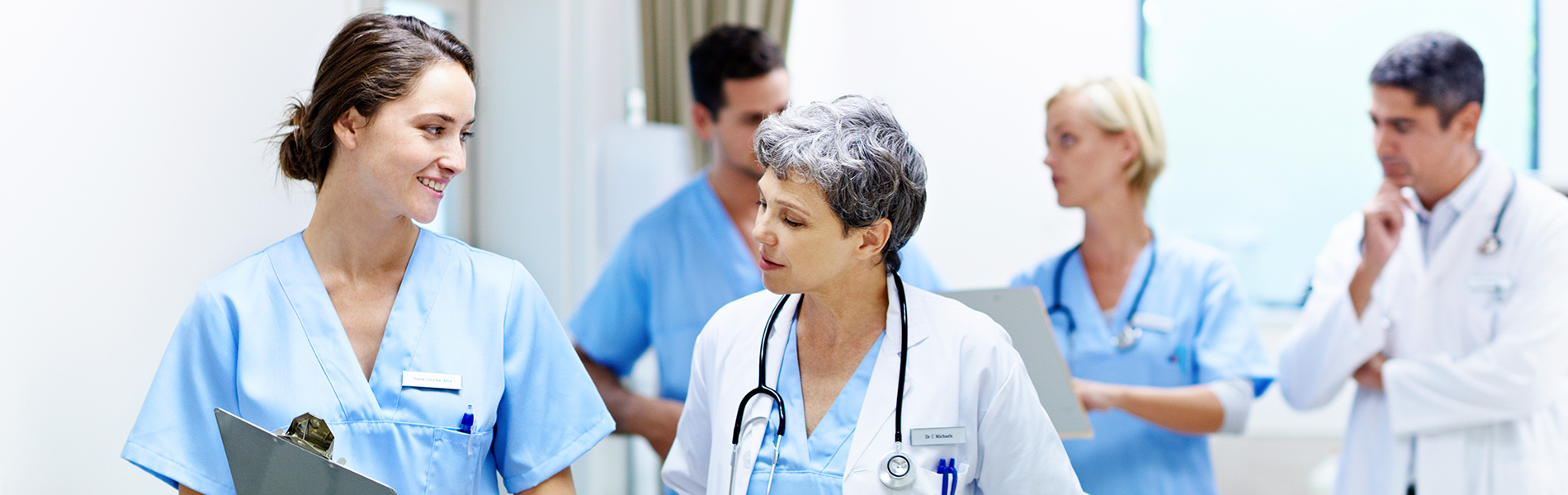 Nurses walking and talking in hospital hallway.