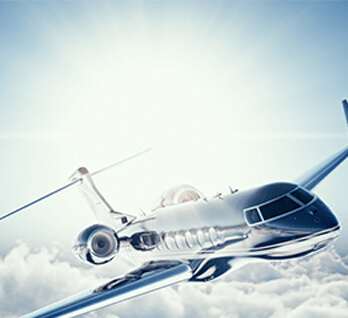 Silver airplane flying above clouds with sun behind Silver airplane flying above clouds with sun behind