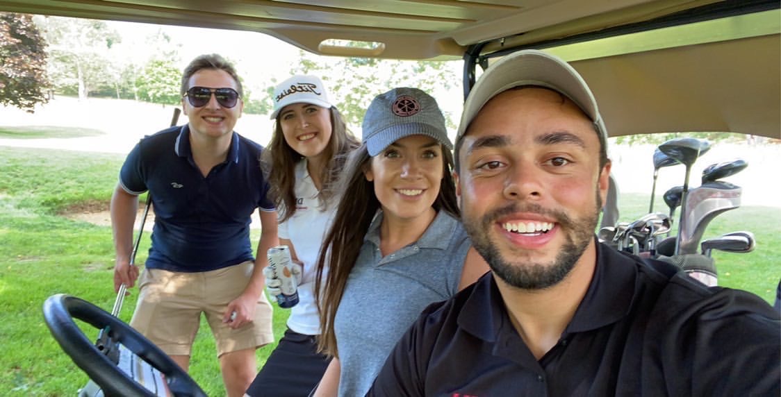 Men and women posing for picture in golf cart