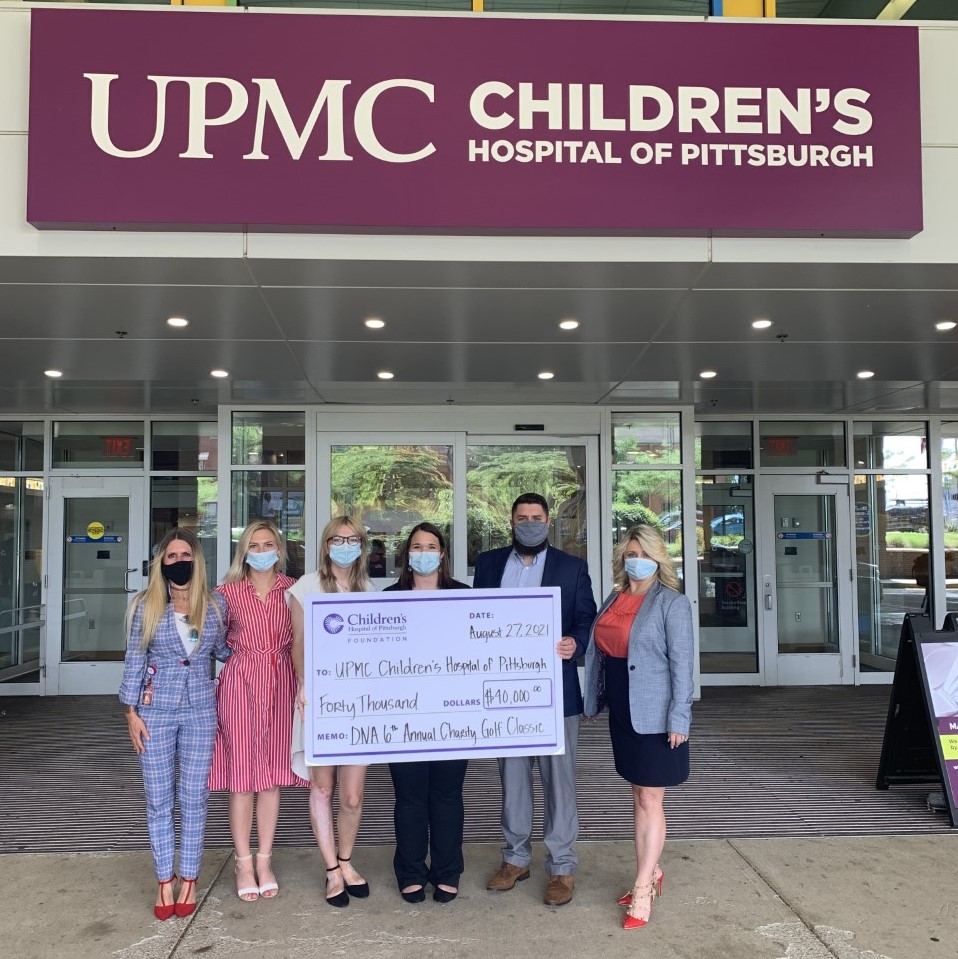 Group of employees with check in front of UPMC Children's Hopsital