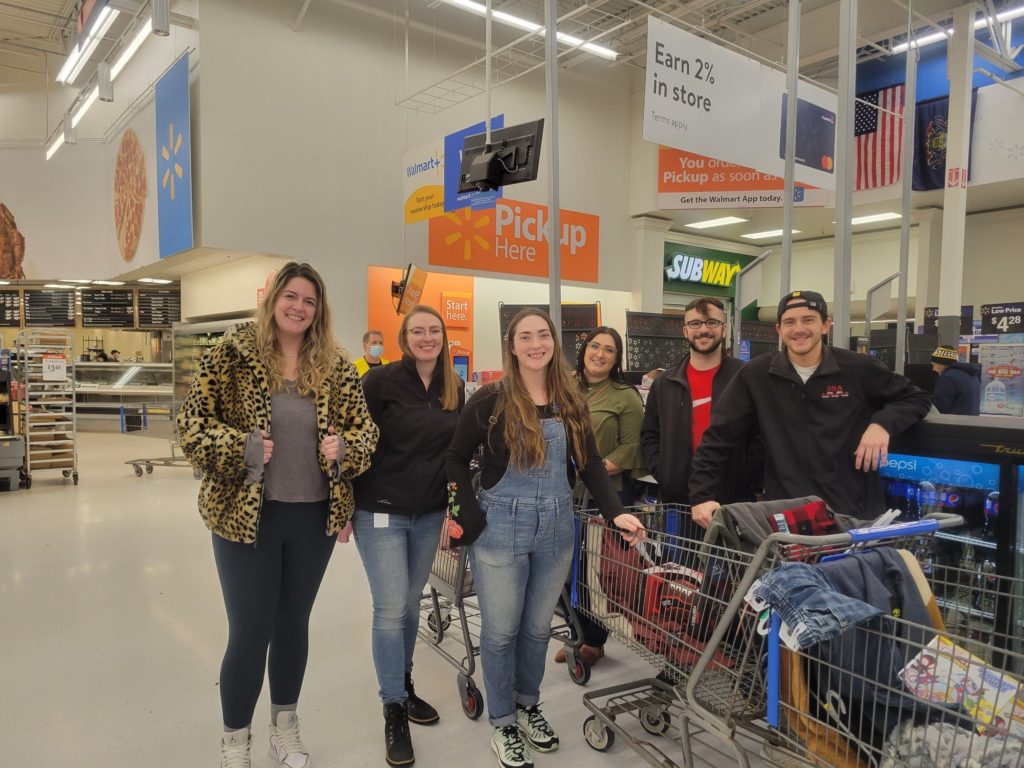 DNA employees posing with shopping carts full of gifts and groceries at Walmart