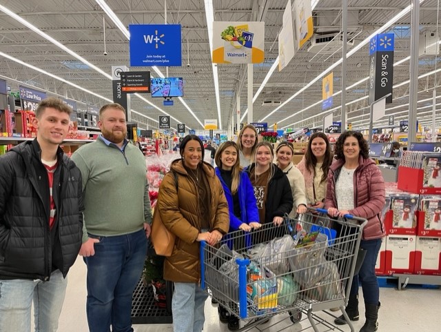 DNA employees with shopping cart full of gifts and groceries in Walmart.