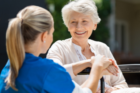 Untitled design (18) Nurse sitting with woman in wheelchair outside