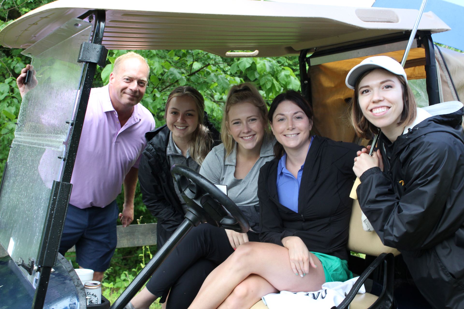 5 golfers posing in a golf cart at a charity golf outing