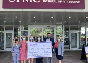 Group of employees with check in front of UPMC Children's Hopsital